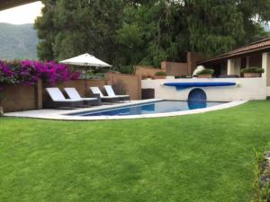 una piscina con sillas y una sombrilla en un patio en Hermosa Casa Tipica en Malinalco en Malinalco