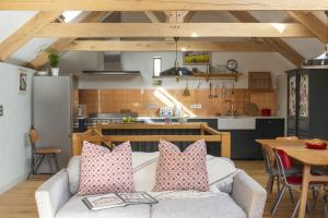 sala de estar con sofá y cocina en The Threshing Barn, en Loddiswell