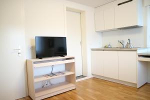 a kitchen with white cabinets and a tv on a stand at Studio CHic in Niederweningen