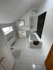 a white bathroom with a tub and a toilet at SOUTH COAST ROOM WITH PARKING SPACE NEAR THE BEACh in Poole