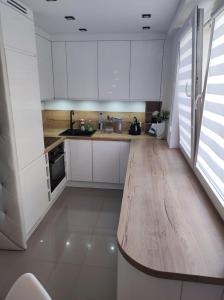 a kitchen with white cabinets and a wooden counter top at Apartament Frombork in Frombork