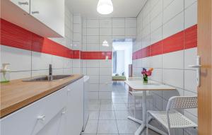 eine Küche mit roten und weißen Kacheln und einem Tisch in der Unterkunft Pet Friendly Apartment In Novalja With Kitchen in Novalja