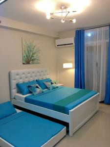 Schlafzimmer mit einem Bett mit blauer Bettwäsche und blauen Vorhängen in der Unterkunft Condo Near Mactan Airport in Cebu City