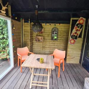 una mesa de madera y 2 sillas en el porche en Tiny house Wassenaar, en Wassenaar