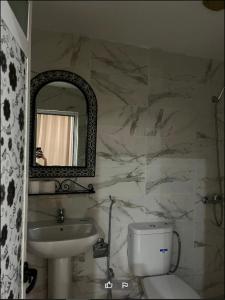 y baño con lavabo, aseo y espejo. en Hotel Jnan Arfoud, en Erfoud