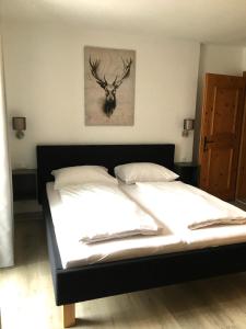 Dormitorio con cama con cabeza de ciervo en la pared en Landhaus Holzereck, en Ehrwald