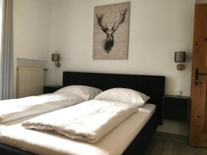 a bed with two pillows and a deer painting on the wall at Landhaus Holzereck in Ehrwald