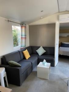 a living room with a blue couch and a bed at Mobil Home - Camping La Falaise in Narbonne