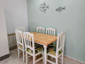 einen Esstisch mit weißen Stühlen und einem Holztisch in der Unterkunft Apartamentos Rodeiramar 2A in Cangas