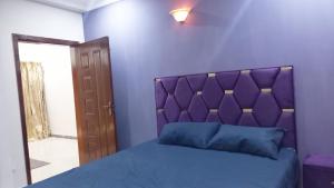 een slaapkamer met een paars bed met een paars hoofdeinde bij Peaceful Low cost 2BR in Islamabad