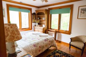 a bedroom with a bed and a chair and windows at Honey Maple Grove BnB in Bedford