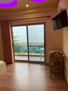 a living room with a large window and a television at Hotel Besa in Shëngjin