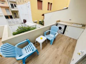 a balcony with two chairs and a washing machine at BEACH APARTMENTS MARINA DI RAGUSA in Marina di Ragusa