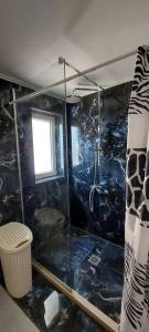 a bathroom with a shower with a black tiled wall at A flower house in Mantoúkion