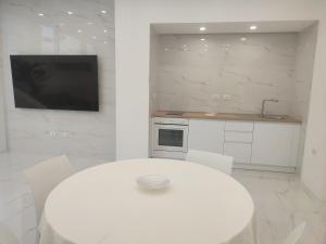 una cucina bianca con tavolo bianco e TV di Elegant basement Suite a Orosei