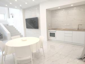 una cucina bianca con tavolo bianco e bancone bianco di Elegant basement Suite a Orosei