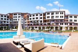 a large swimming pool with chairs and a building at Apartments in complex Harmony hills in Rogachevo