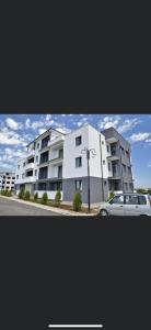 a white building with a car parked in front of it at Apartment la mare in Agigea