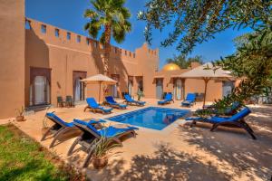 an outdoor swimming pool with blue chairs and umbrellas at Taj Atlas Wellness Boutique Hôtel & Spa in Amizmiz
