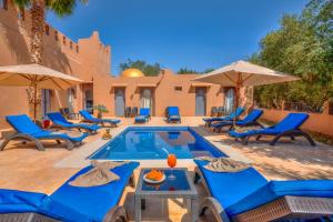 une terrasse avec des chaises bleues et une piscine dans l'établissement Taj Atlas Wellness Boutique Hôtel & Spa, à Amizmiz