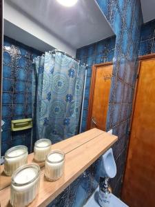 uma casa de banho com paredes de azulejos azuis e uma prateleira de madeira com frascos em Nonna Dorina Casa Vacanze em Pietrabbondante