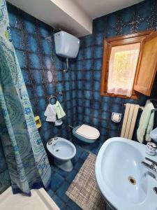 bagno piastrellato blu con lavandino e servizi igienici di Nonna Dorina Casa Vacanze a Pietrabbondante