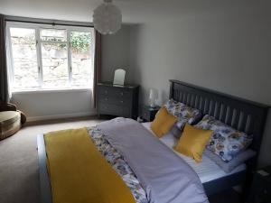 sypialnia z łóżkiem z żółtymi poduszkami i oknem w obiekcie Applegrove, perfect 2 bed bungalow, Fortrose w mieście Fortrose