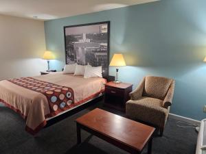 a hotel room with a bed and a chair at budgetel Inn & Suites in Moody