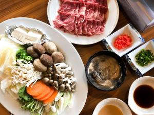 a table topped with plates of food with meat and vegetables at Breezbay Seaside Resort Matsushima in Matsushima