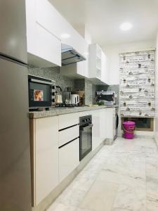 a kitchen with white cabinets and a marble floor at THE luxurious and romantic pearl apartment in Mohammedia