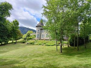una casa vieja en un campo con árboles y hierba en Chateau Ol Puech, en Vic-sur-Cère