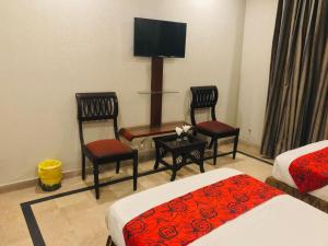 um quarto de hotel com duas camas e duas cadeiras e uma televisão de ecrã plano em Pool & Park Hotel em Lahore
