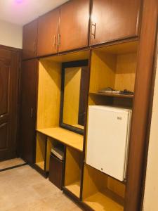 a small kitchen with wooden cabinets and a refrigerator at Pool & Park Hotel in Lahore