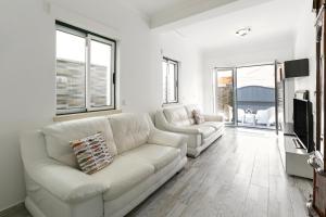 a white living room with a couch and a tv at Lazy House in Nazaré