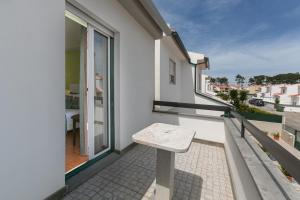 a bench on the balcony of a white apartment at Lazy House in Nazaré