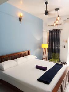 um quarto com uma cama branca e uma toalha azul em Omkara - The Fives Guest house em Tiruvannamalai