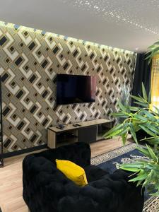 a living room with a black couch and a tv at Charme et confort in Mulhouse