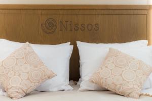 a bed with white pillows and a wooden headboard at Nissos Apartments in Myrina