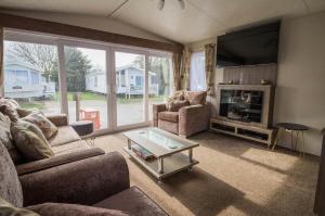 uma sala de estar com um sofá, uma mesa e uma televisão em Modern 6 Berth Caravan At Highfield Grange In Essex Ref 26609p em Clacton-on-Sea
