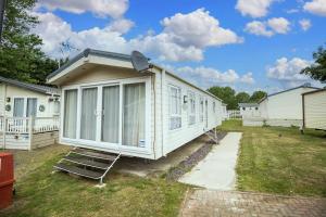 a small white house with chairs in a yard at Modern 6 Berth Caravan At Highfield Grange In Essex Ref 26609p in Clacton-on-Sea