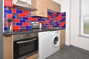 uma cozinha com uma máquina de lavar roupa e uma parede de azulejos coloridos em Smithfield Apartments - Gated Executive City Centre Apartments em Stoke-on-Trent