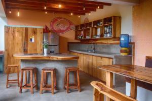 Vistamar Guest House في أيامبي: مطبخ مع دواليب خشبية وكاونتر مع الكراسي