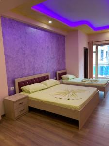 duas camas num quarto com uma parede roxa em Hotel Besa em Shëngjin