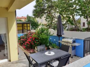 a patio with a table and an umbrella and flowers at Apartman Nada in Ližnjan