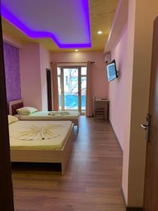 two beds in a room with a purple ceiling at Hotel Besa in Shëngjin