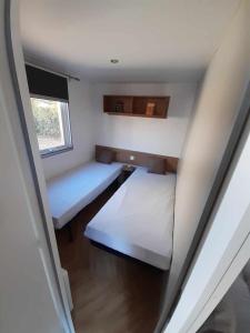 a small room with two beds and a window at Mobil Home Ronce Les Bains in Ronce-les-Bains