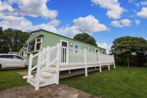 a green house with a white porch and a car at Great 8 Berth Caravan For A Staycation In Clacton-on-sea Ref 26436e in Clacton-on-Sea