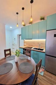 a kitchen with a table with three chairs and a refrigerator at Rafaela Sea Apartment in Sarandë