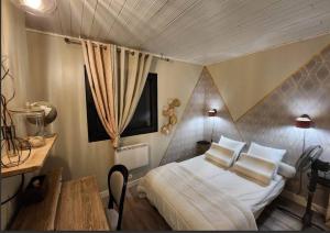 una camera da letto con un letto con cuscini bianchi e un tavolo di Sublime maison - LA PERLA a Meschers-sur-Gironde