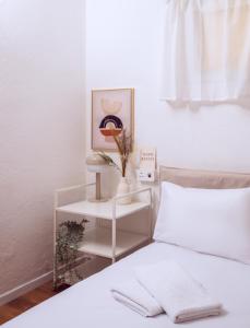 - une chambre avec un lit blanc et une table de nuit à côté dans l'établissement Downtown by the beach apartment, à Tel Aviv